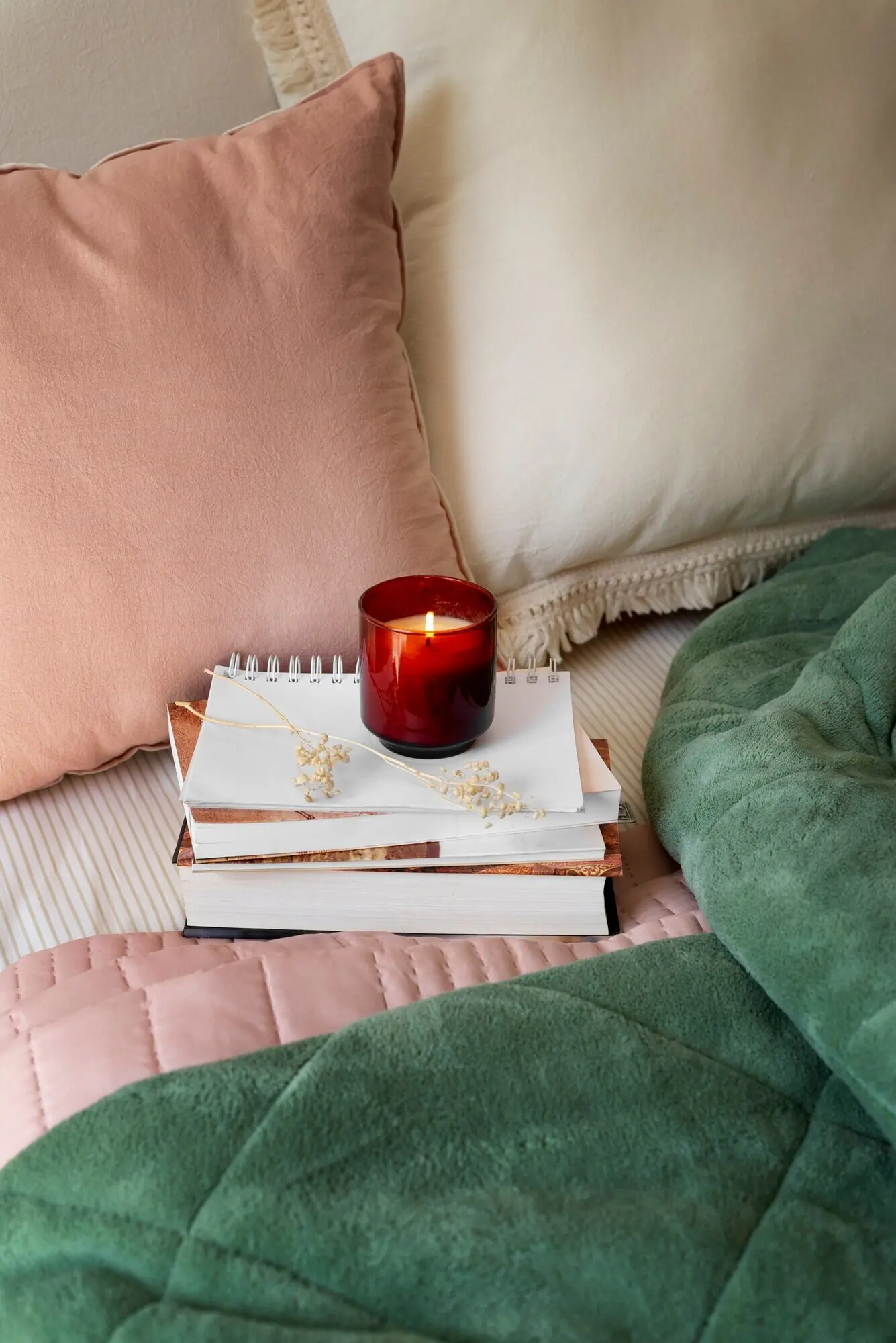 Aufnahme aus hoher Perspektive eines gemütlichen Bettarrangements mit Notizbuch.